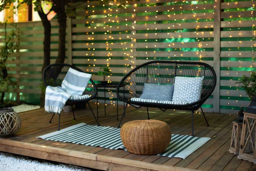 Backyard patio with furniture, twinkle lights, and an outdoor rug.