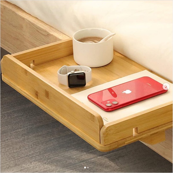 Image of a clamp-on bedside shelf with a book, phone, smart watch, and cup sitting on top