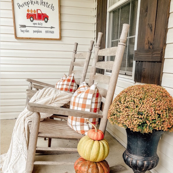 Two rocking chairs on a porch with pillows and a blanket