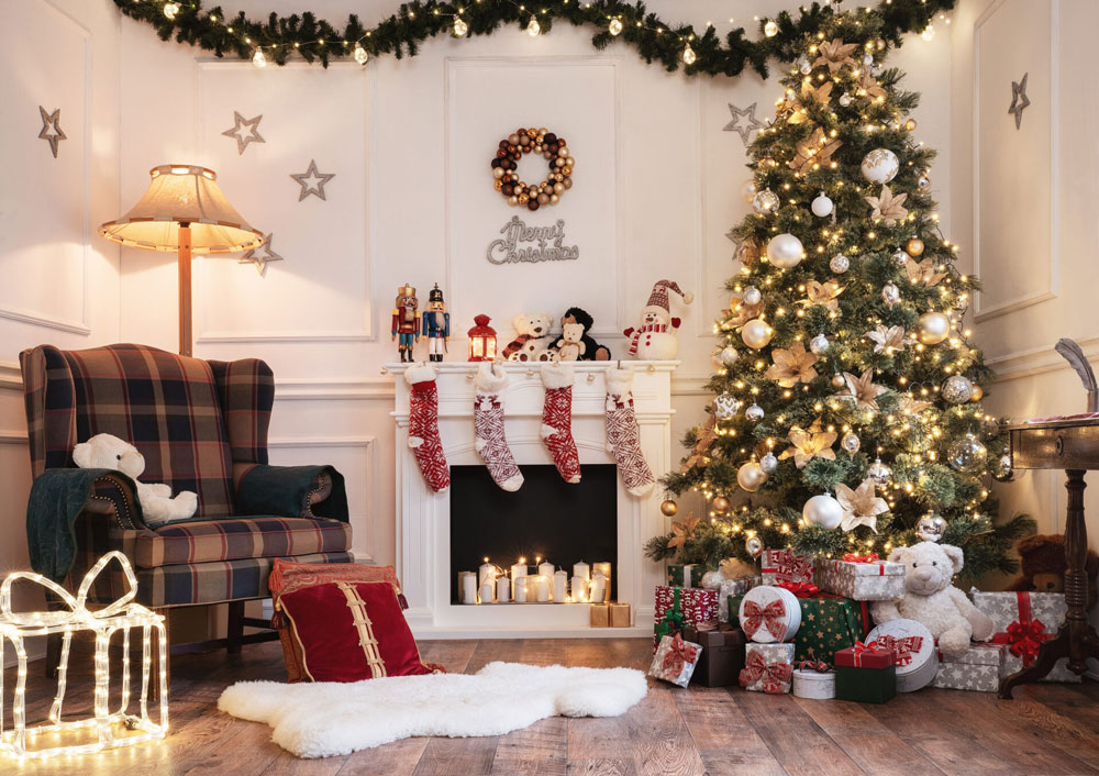 A living space decorated for the holidays with stockings on the fireplace mantle, a lit up tree, and wrapped presents underneath.