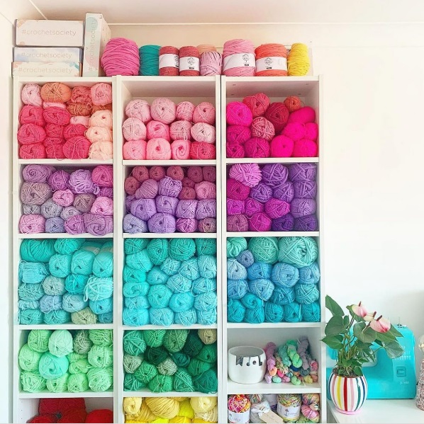 Tall cubbies with color-coded sheaves of yarn on each shelf.