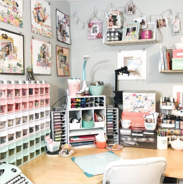 A corner crafting desk with photos and art on the walls around it.
