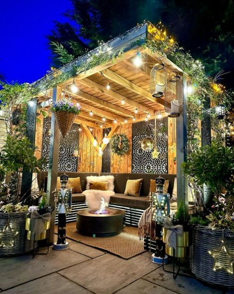A pergola-covered patio decorated for the holidays with lights, plants, and nutcrackers