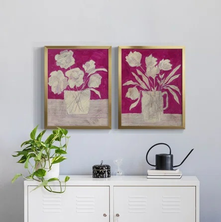 Magenta floral wall art displayed on a neutral wall and hung over a white cabinet.