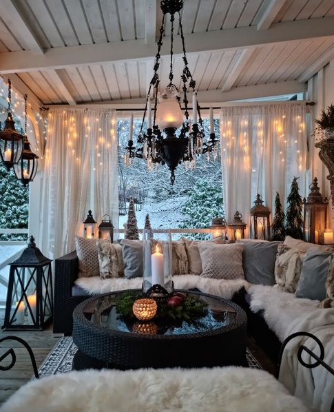 Enclosed winter patio decorated with string lights, lanterns, and candles