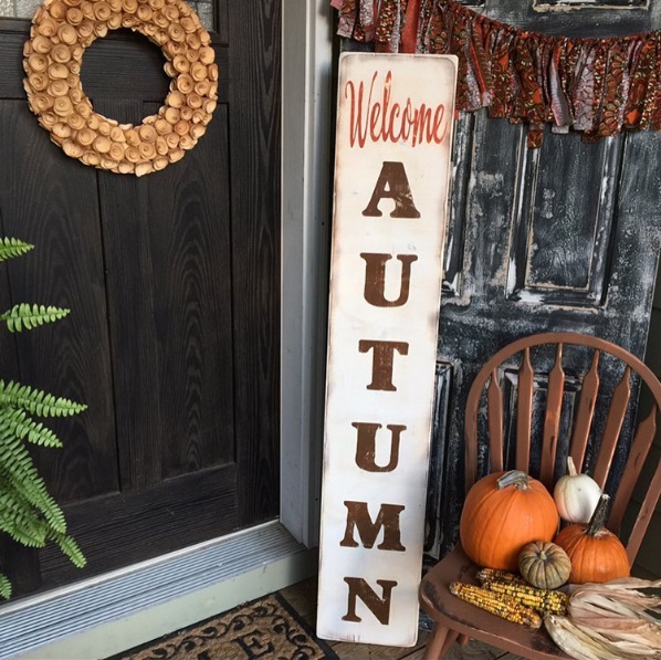 A long, vertical sign that reads "welcome autumn" set in front of a door