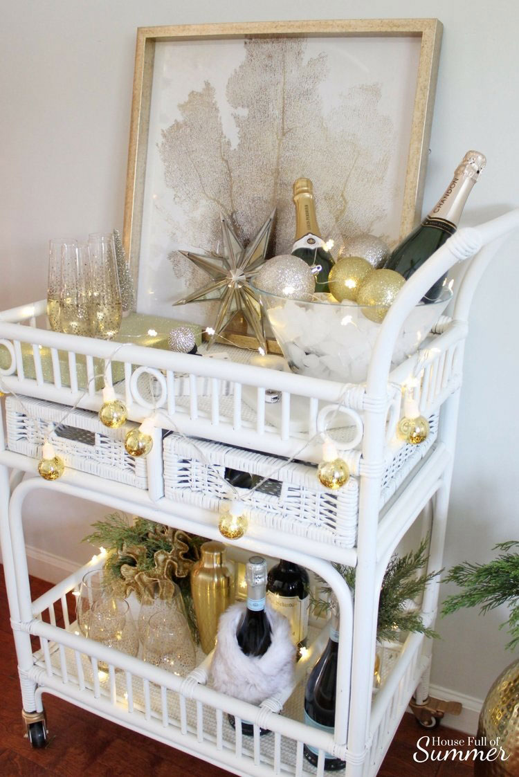White bar cart decorated with gold ornaments and string lights.