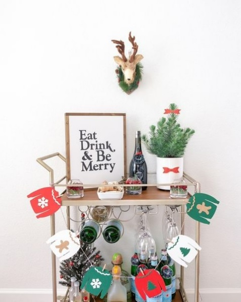 Festive bar cart with an Eat, Drink, & Be Merry sign and papercraft holiday sweaters banner.