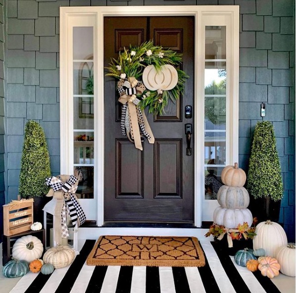 Front porch decorated for fall with pumpkins, a doormat, and a wreath