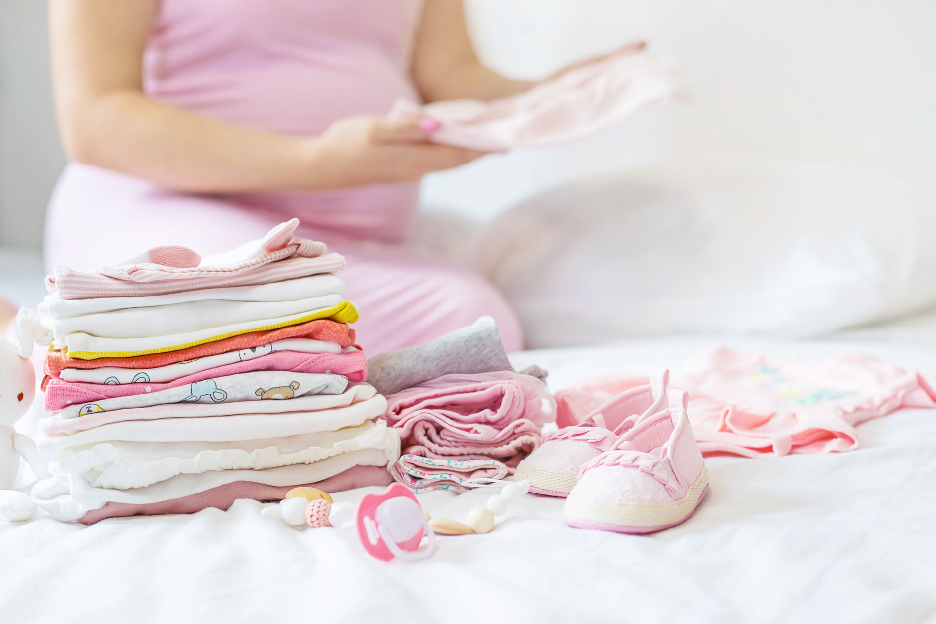 A pregnant woman sorting through baby things and folding baby clothes