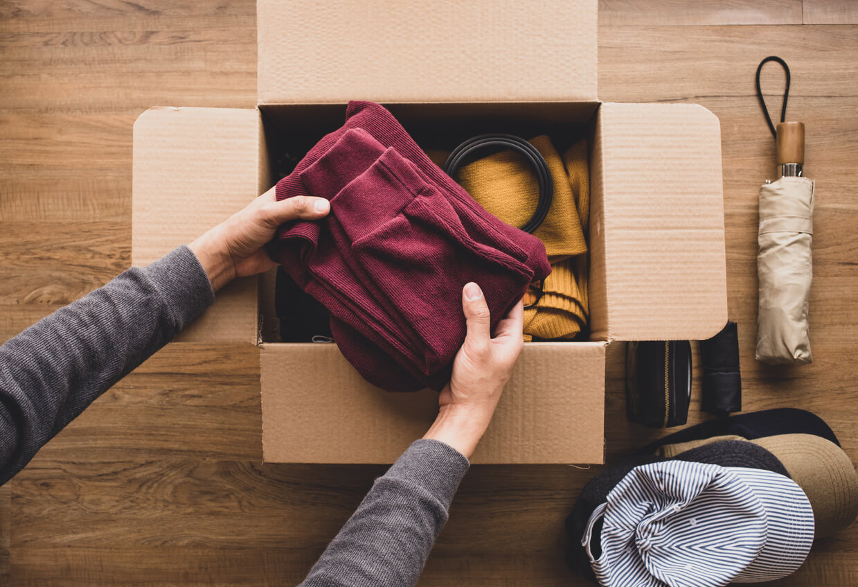 placing folded sweaters into a cardboard box