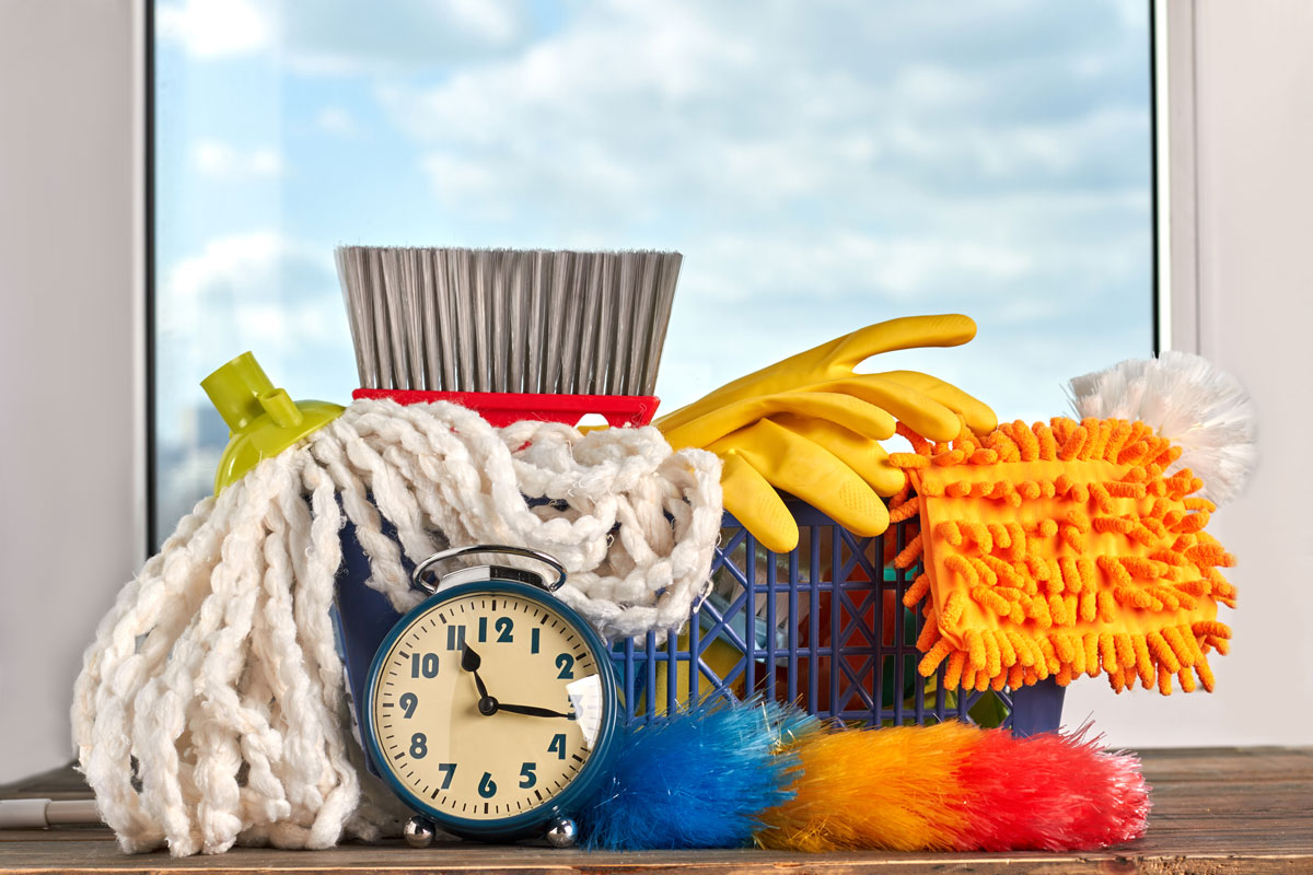 A timer on a table next to a bin of cleaning supplies