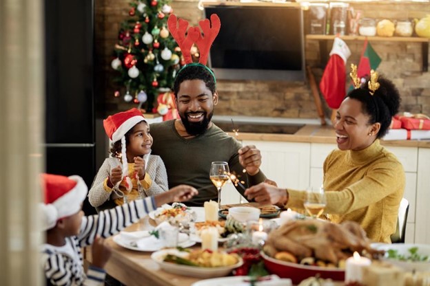 a family is wearing festive accessories and sitting around a table full of holiday food