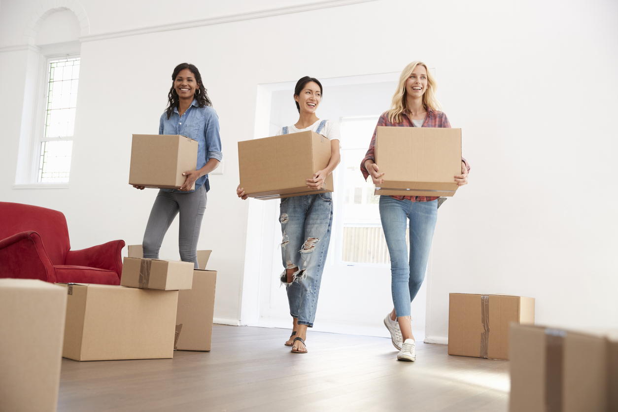 Three Female Friends Carrying Boxes Into New Home On Moving Day