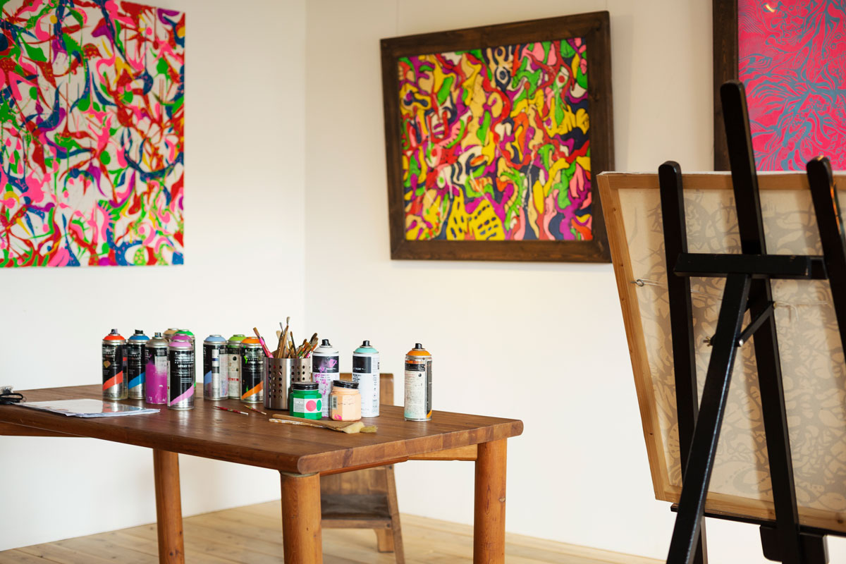 Interior view or art gallery with studio space, easels and cans of spray paint on a table.