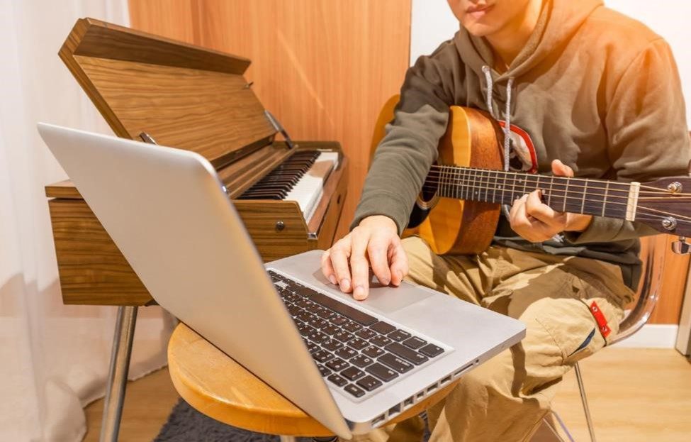 Man recording music on his guitar and keyboard