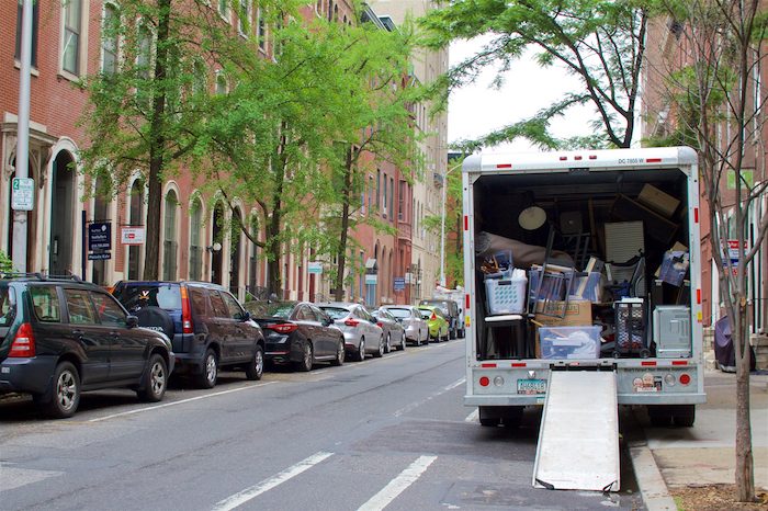 A moving truck packed with items to move on a busy street.
