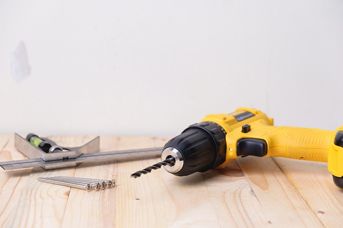 Yellow drill and tools on wooden table