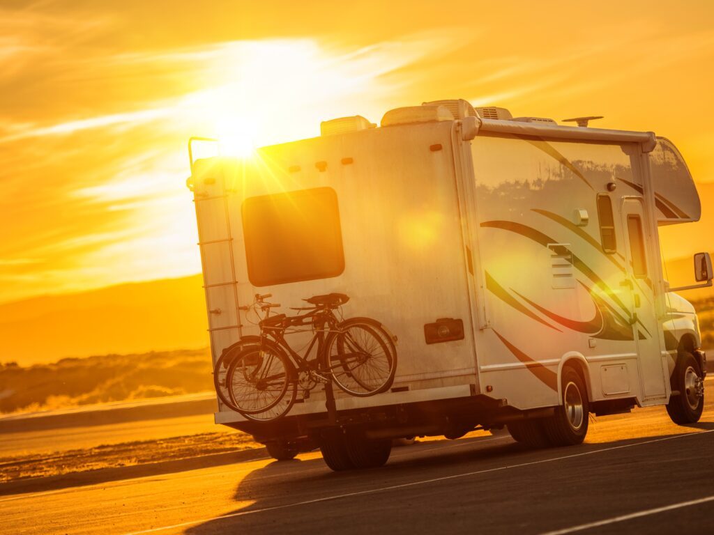 RV Camper with bikes driving towards the sunset