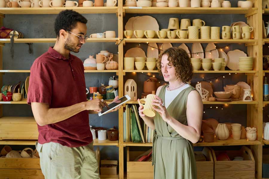 Two people tracking inventory of ceramic mugs