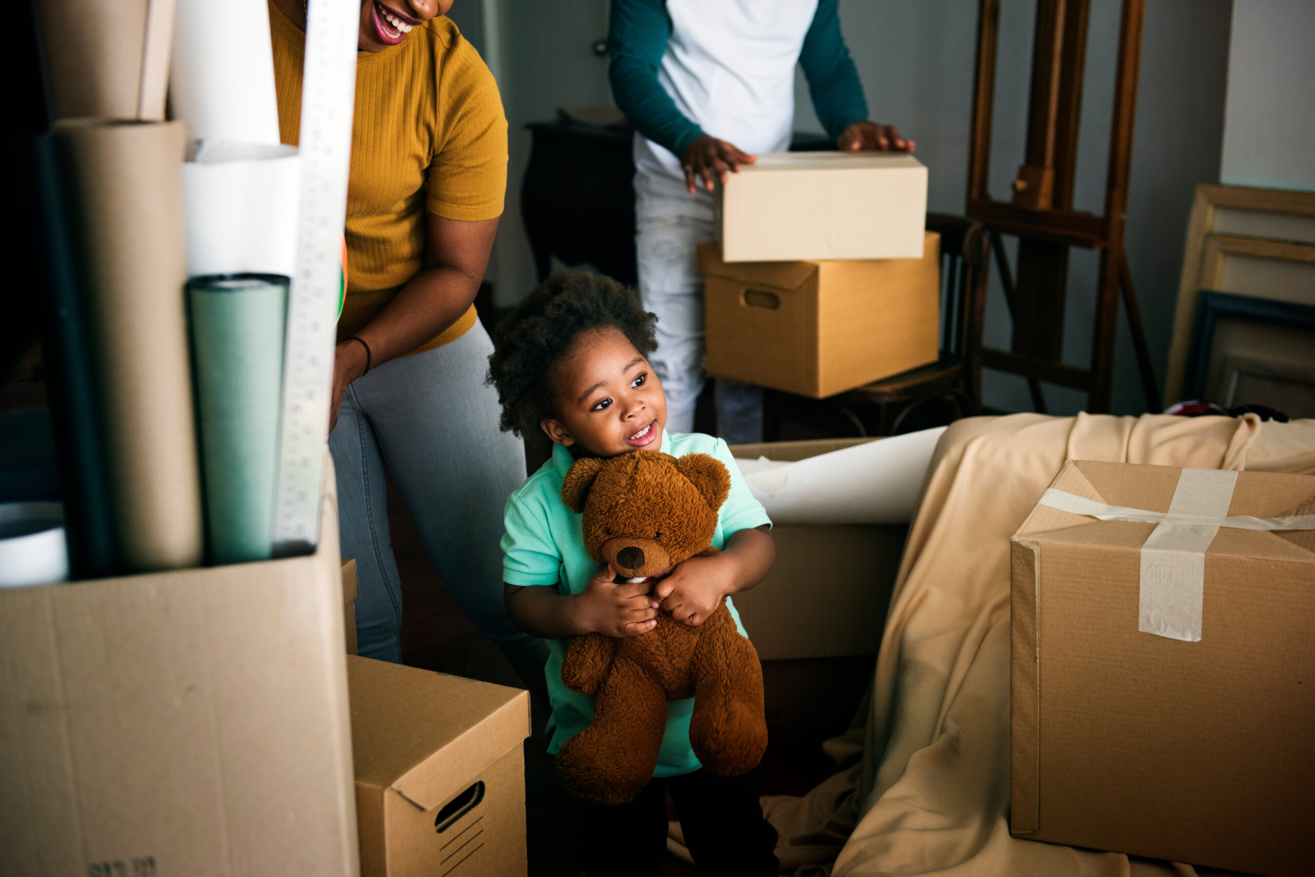 Family packing up boxes for a home move. Child holding teddy bear